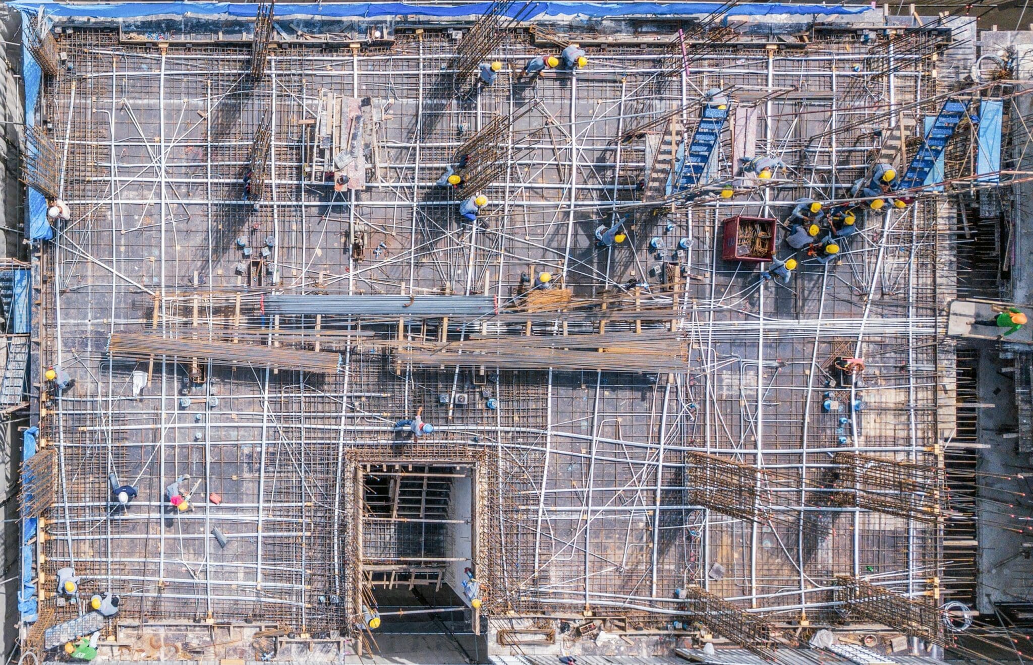 Aerial view of a large construction site with workers and rebar
