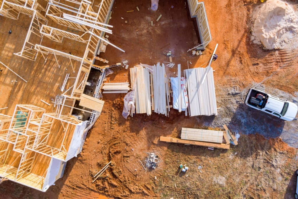 Aerial view of a construction site with wooden house frames and building materials.