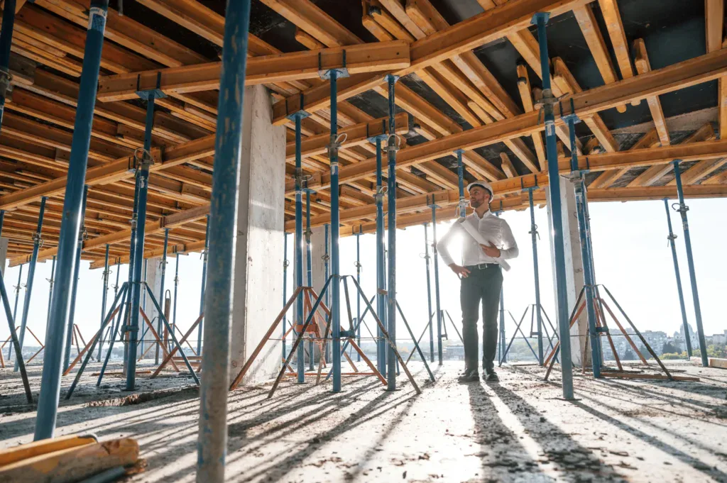 Man in hard hat and white shirt stands on concrete floor at construction site