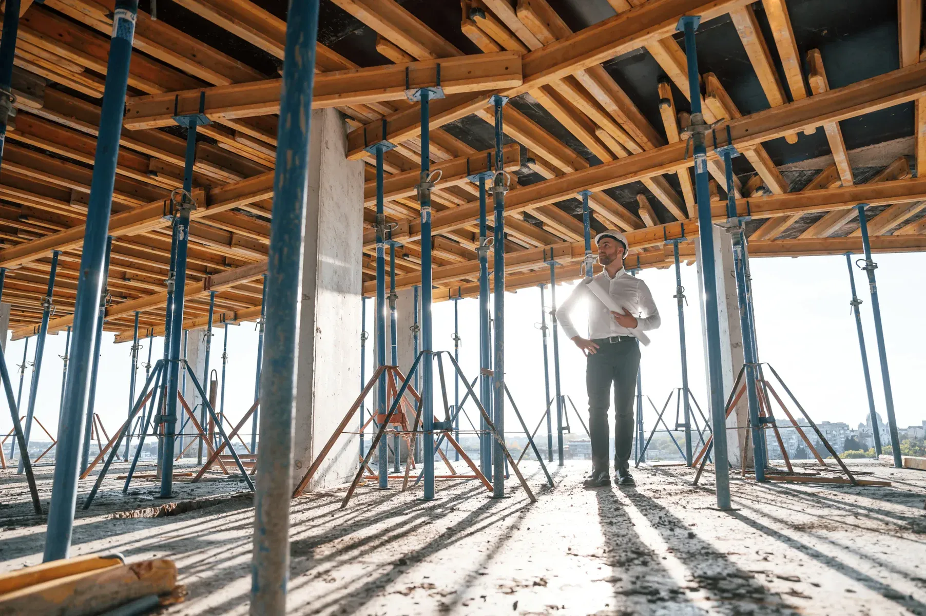 Man in hard hat and white shirt stands on concrete floor at construction site