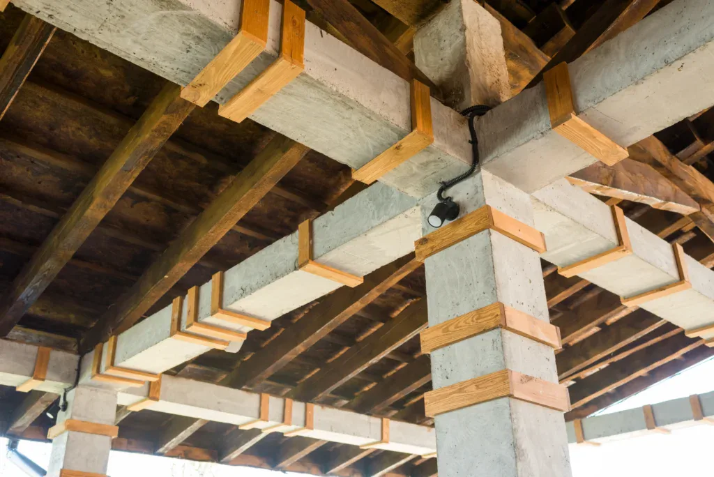 Concrete and wood ceiling structure with exposed beams and a light fixture.