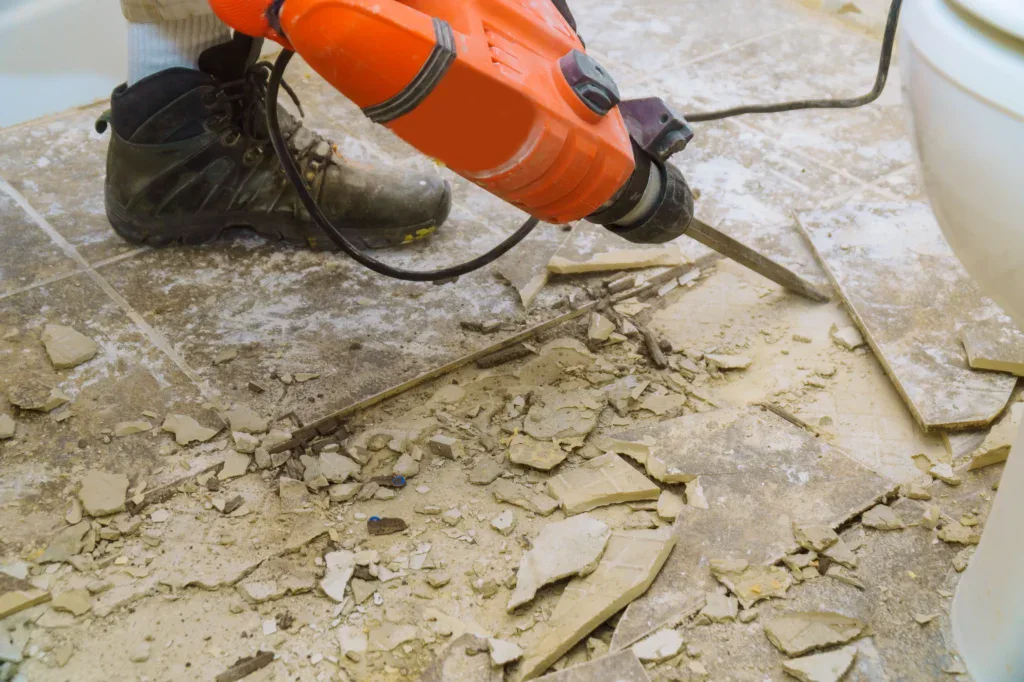 Person using a jackhammer to remove old floor tiles