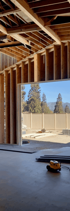 Interior of a house under construction with exposed wooden beams and a large opening.