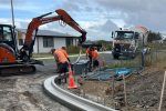 Heavy construction work happening on road with workers and machinery.