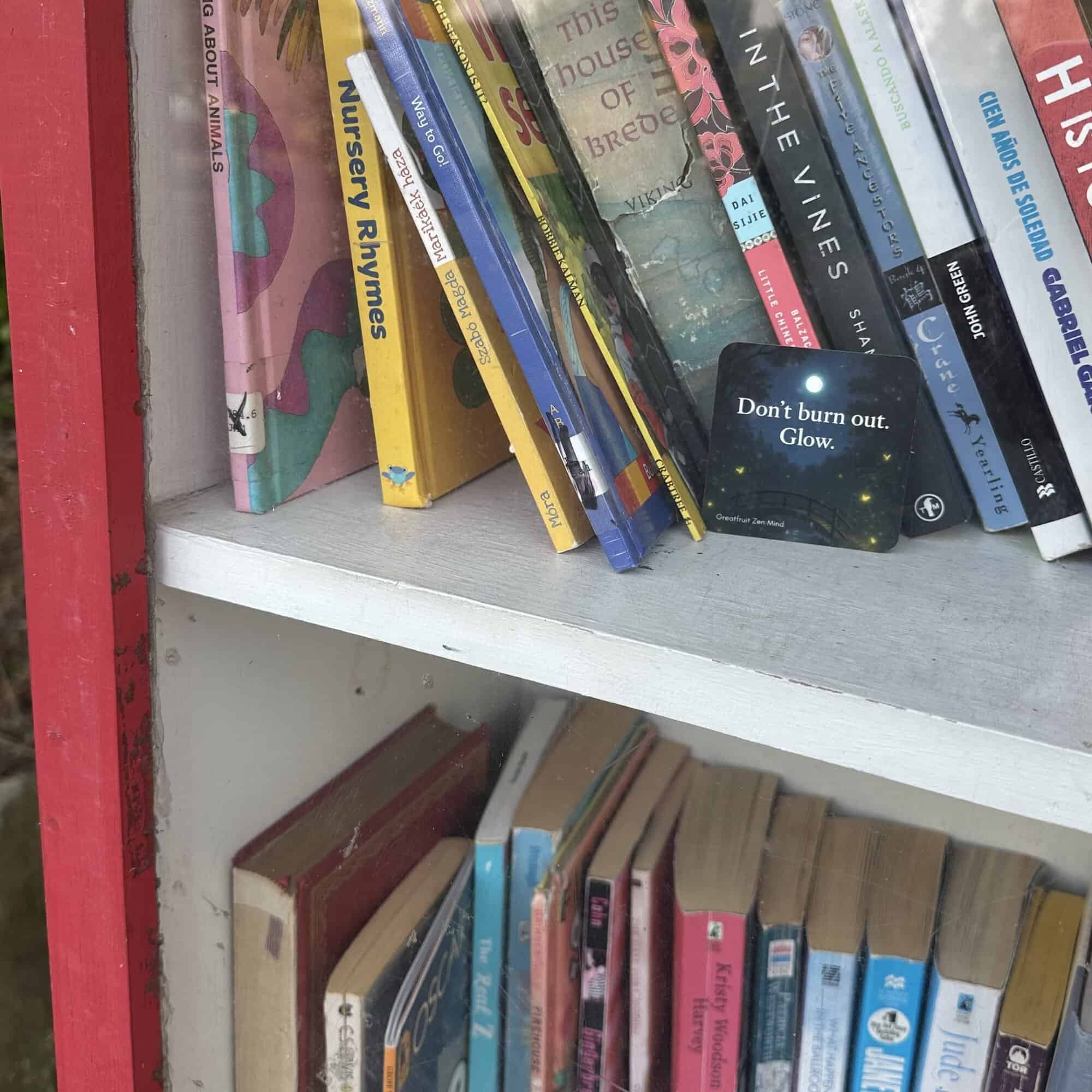 A Pocketful of Zen card setting on the bookshelf inside and outdoor lending library. Text reads: Don't burn out. Glow.
