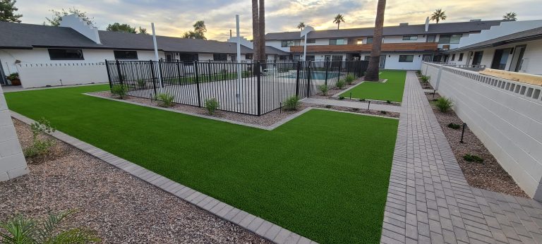 Beautiful backyard landscaping with synthetic grass and paved walkways.
