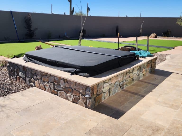 Artificial turf and stone fire pit in a modern backyard landscape design.