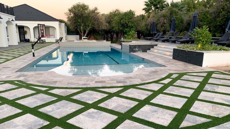Luxurious landscaped pool area featuring greenery, modern planters, and stylish lounge chairs.