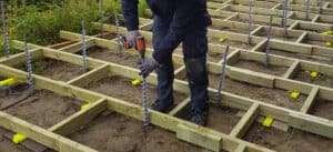 Carpenter building a multi-leveled wooden deck using GroundPlug® Screw Pile Foundations.