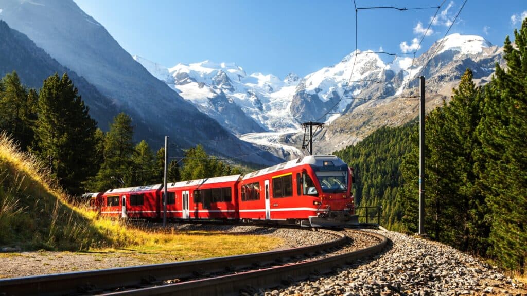 A red train travelling through the Swiss Alps.