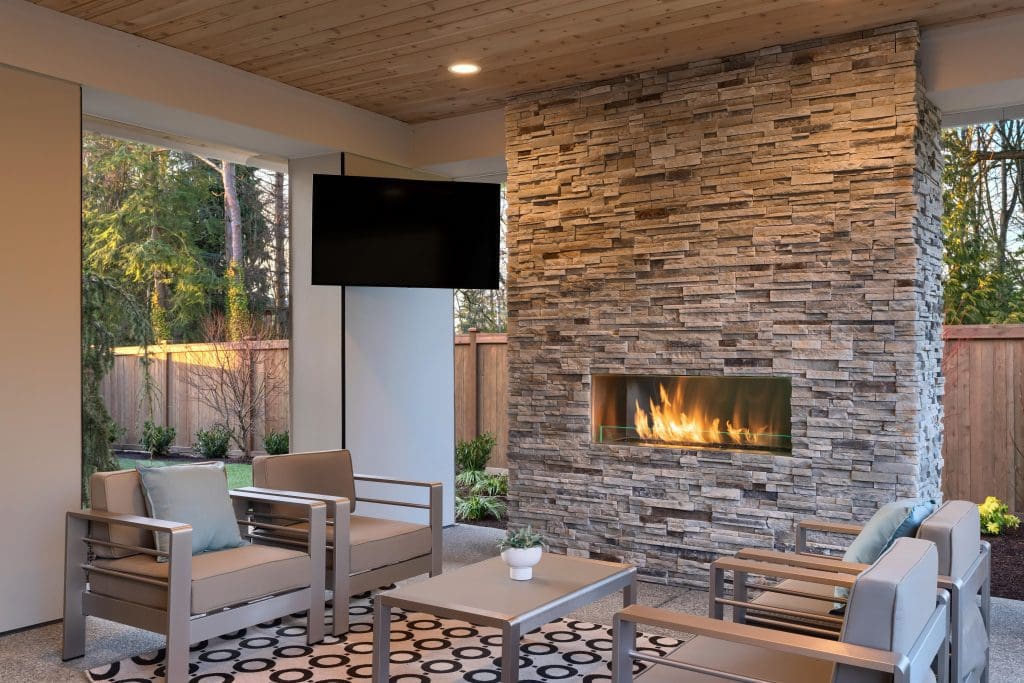 Outdoor patio with stone fireplace, television, and modern seating area.