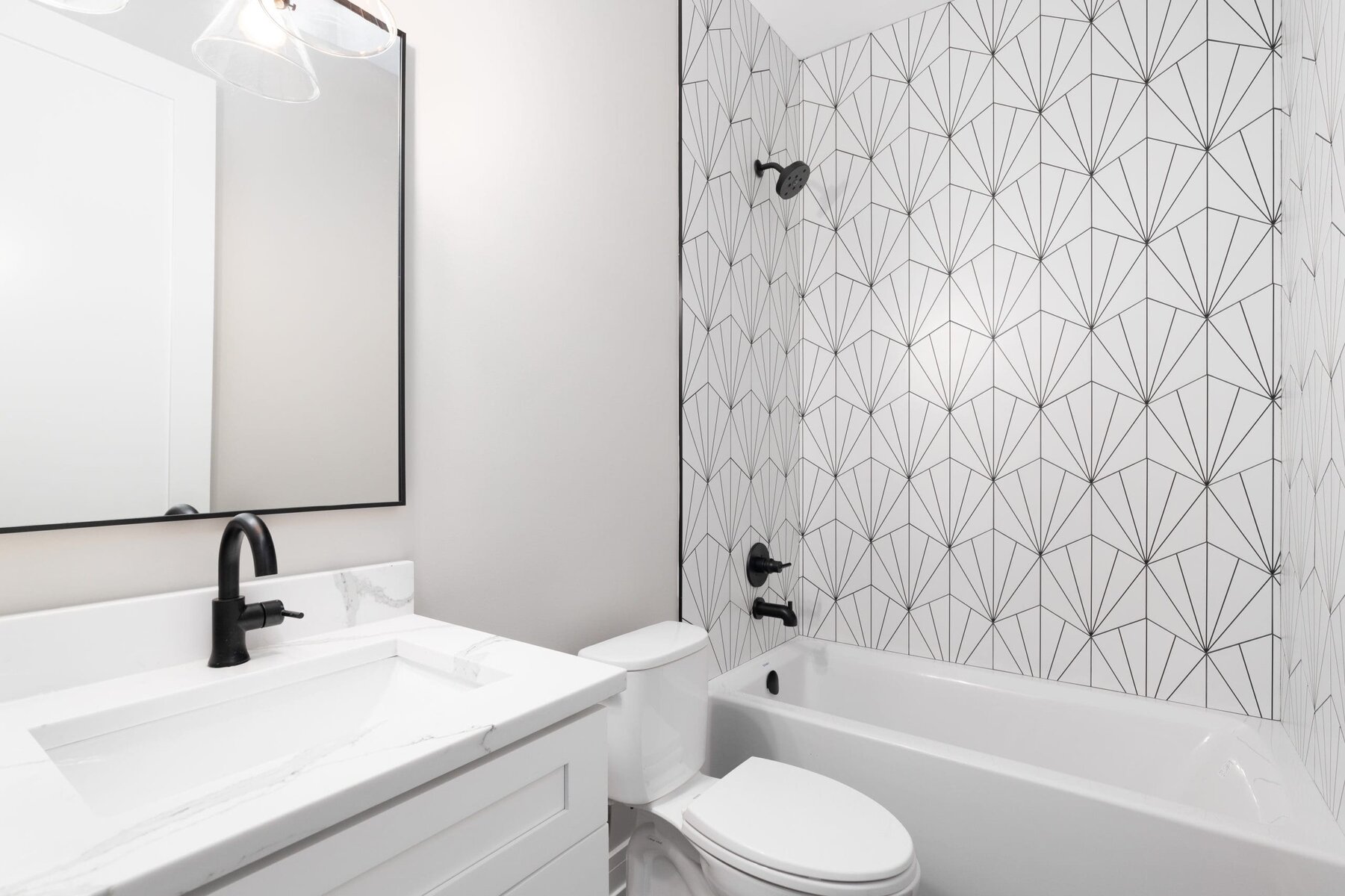 Modern bathroom with white walls, black fixtures, and patterned shower tiles.