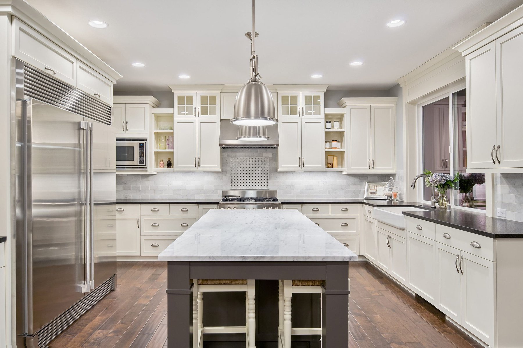 Modern kitchen with white cabinets, dark countertops, and a large island.