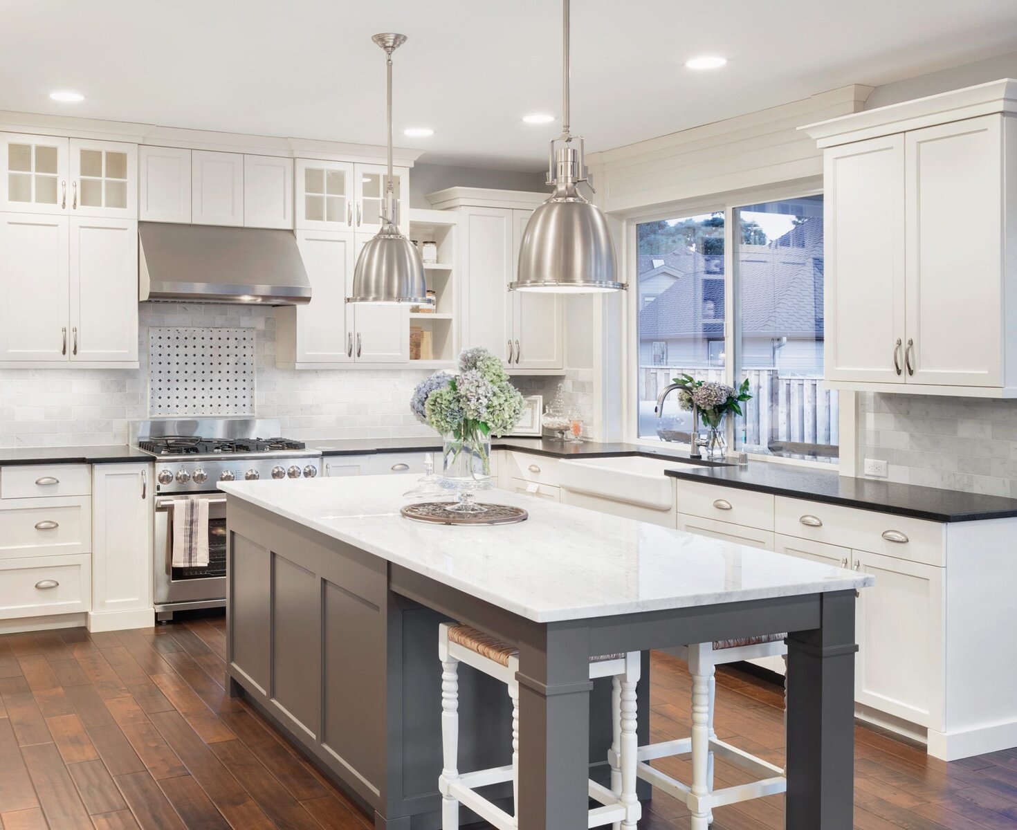 Modern kitchen with white cabinets, dark island, and stainless steel appliances