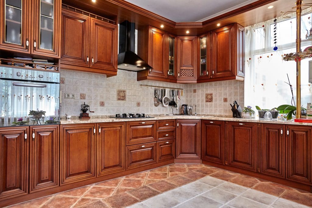 Well-lit kitchen with wooden cabinets, tiled floor, and modern appliances.