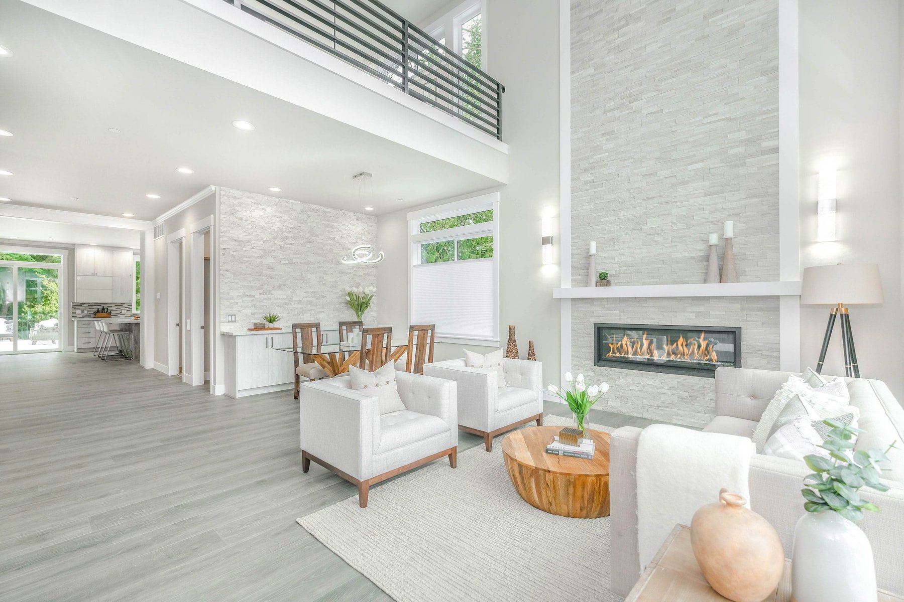 Modern living room with fireplace, white furniture, and dining area.
