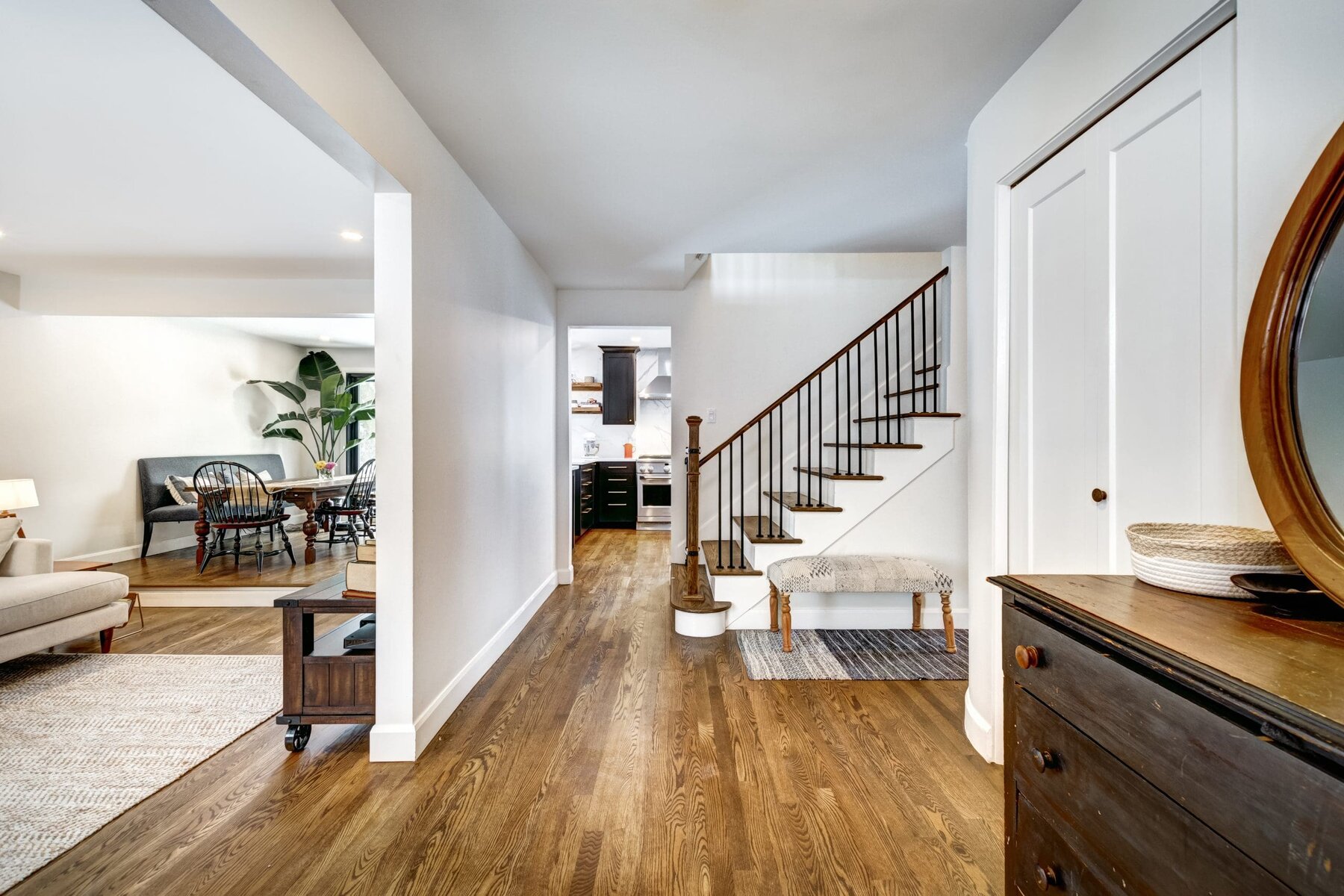 A home interior with wooden floors, a staircase, and a glimpse of a living area.