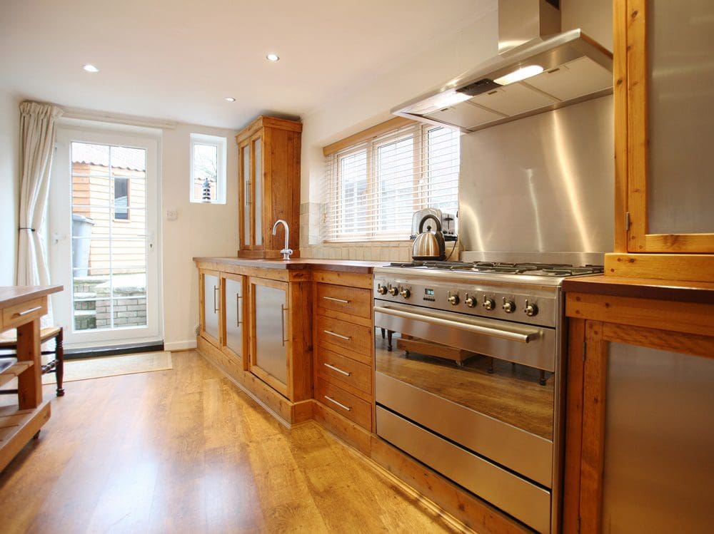 A kitchen with wooden cabinets, stainless steel appliances, and a white door.