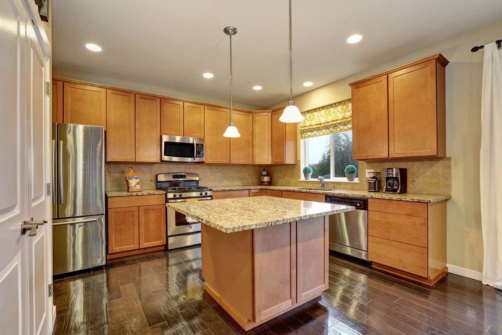Modern kitchen with light wood cabinets, stainless steel appliances, and granite countertops.