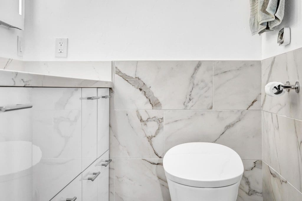 Modern bathroom with white marble tiles and a white toilet