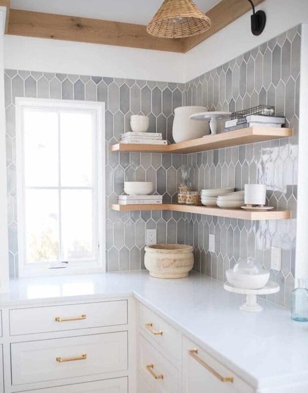 Kitchen corner with grey picket tile, white cabinets, and wooden shelves.