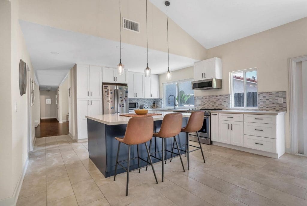 Modern kitchen with white cabinets, dark island, and three bar stools