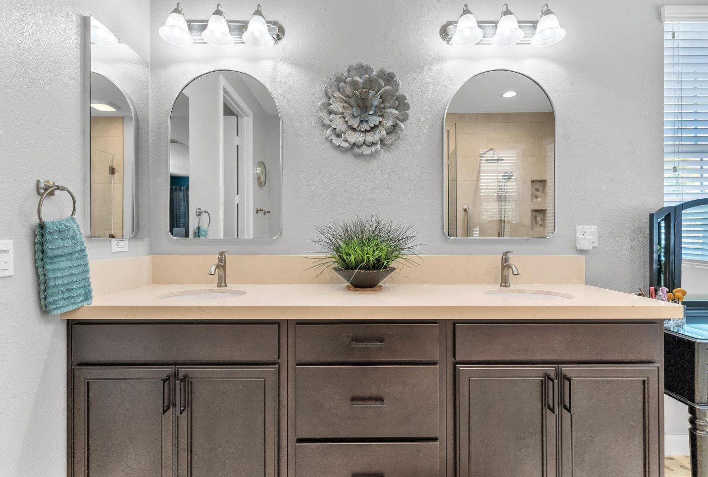 Double vanity with arched mirrors, light fixtures, and a decorative flower.