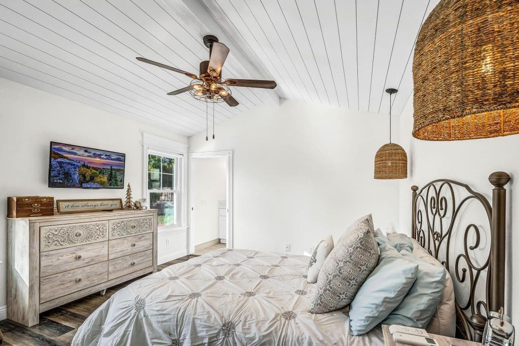 Bedroom with a bed, dresser, TV, and woven light fixtures.