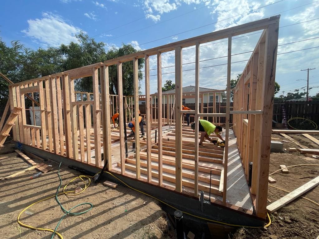 Workers framing a house under construction on a sunny day