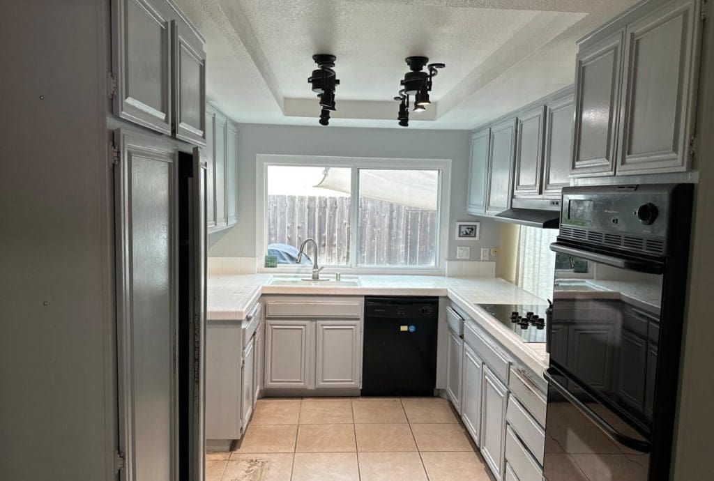 U-shaped kitchen with light gray cabinets, white countertops, and black appliances.