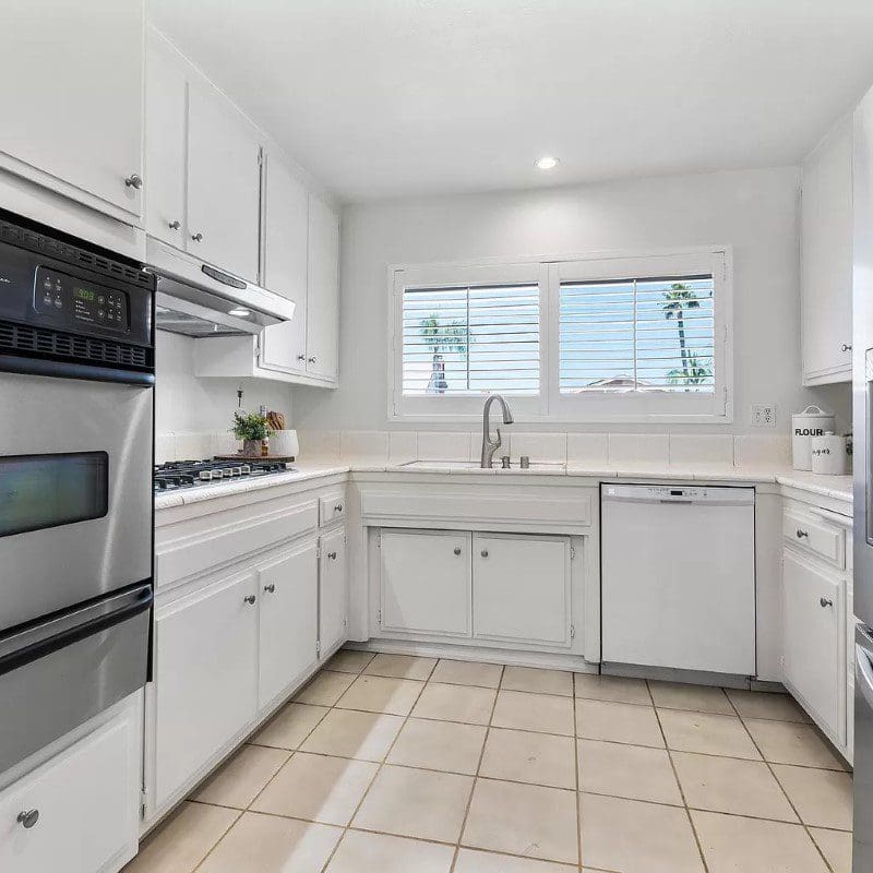 Bright white kitchen with stainless steel appliances and window