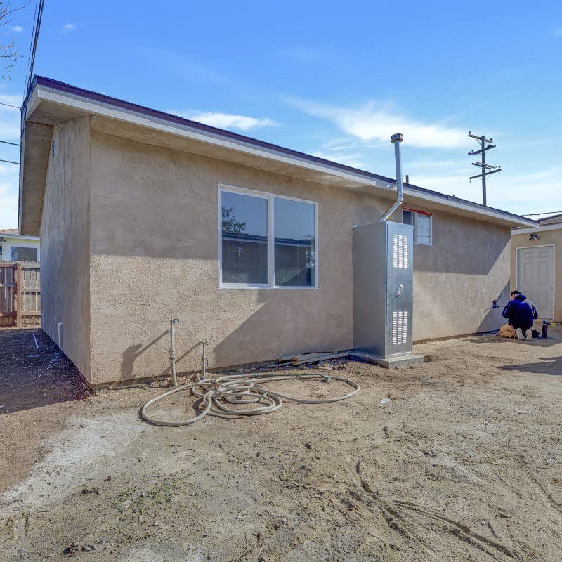 Exterior view of a stucco building with a person working outside.
