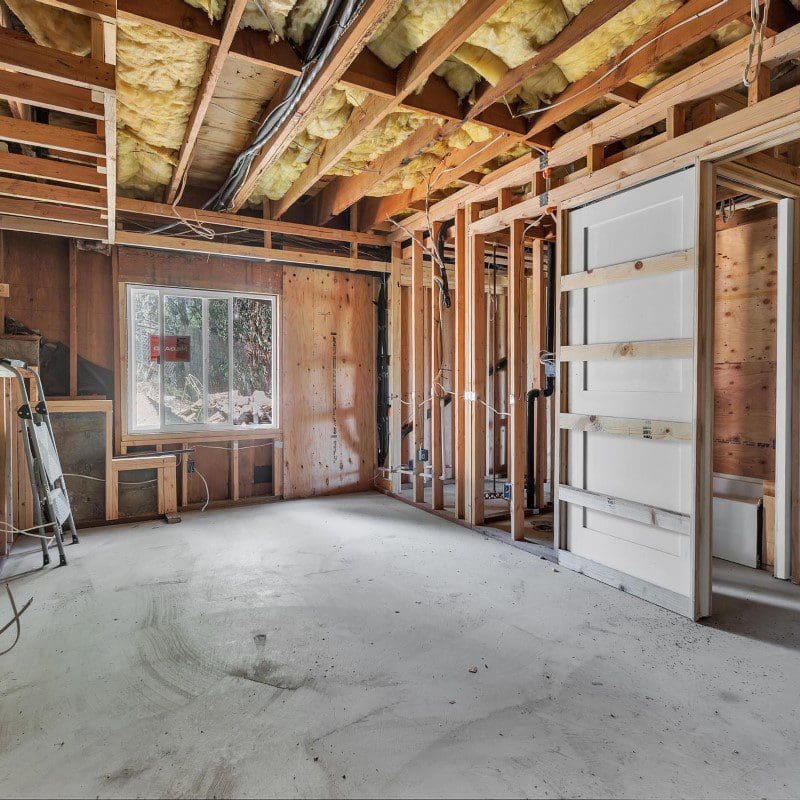 Unfinished basement with exposed wooden beams, insulation, and concrete floor.