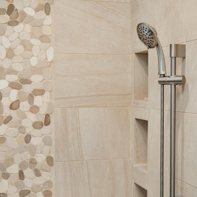 Modern shower with pebble and large rectangular tiles, and a handheld showerhead.