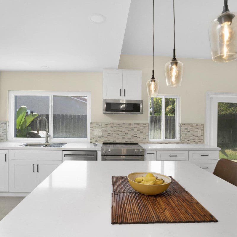 Modern kitchen with white cabinets, stainless steel appliances, and a large island.
