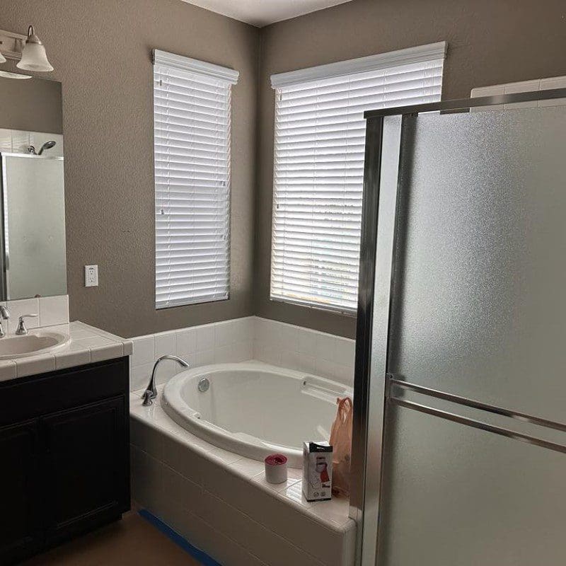 Bathroom with a white bathtub, dark vanity, and shower stall.