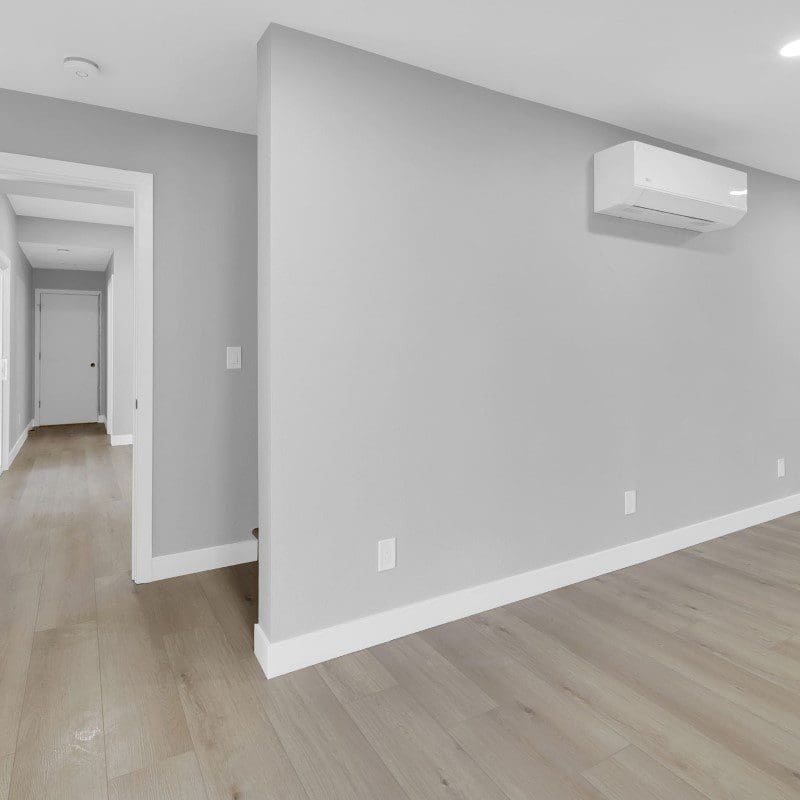 Empty room with light gray walls, light wood floor, and white trim.