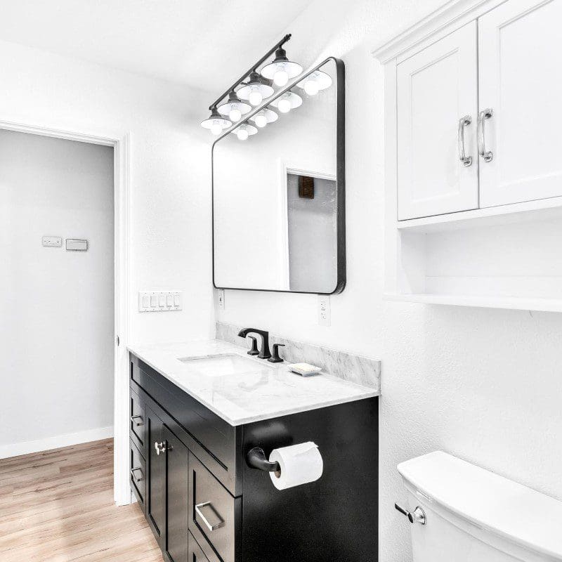 Modern bathroom with black vanity, white marble counter, and large mirror