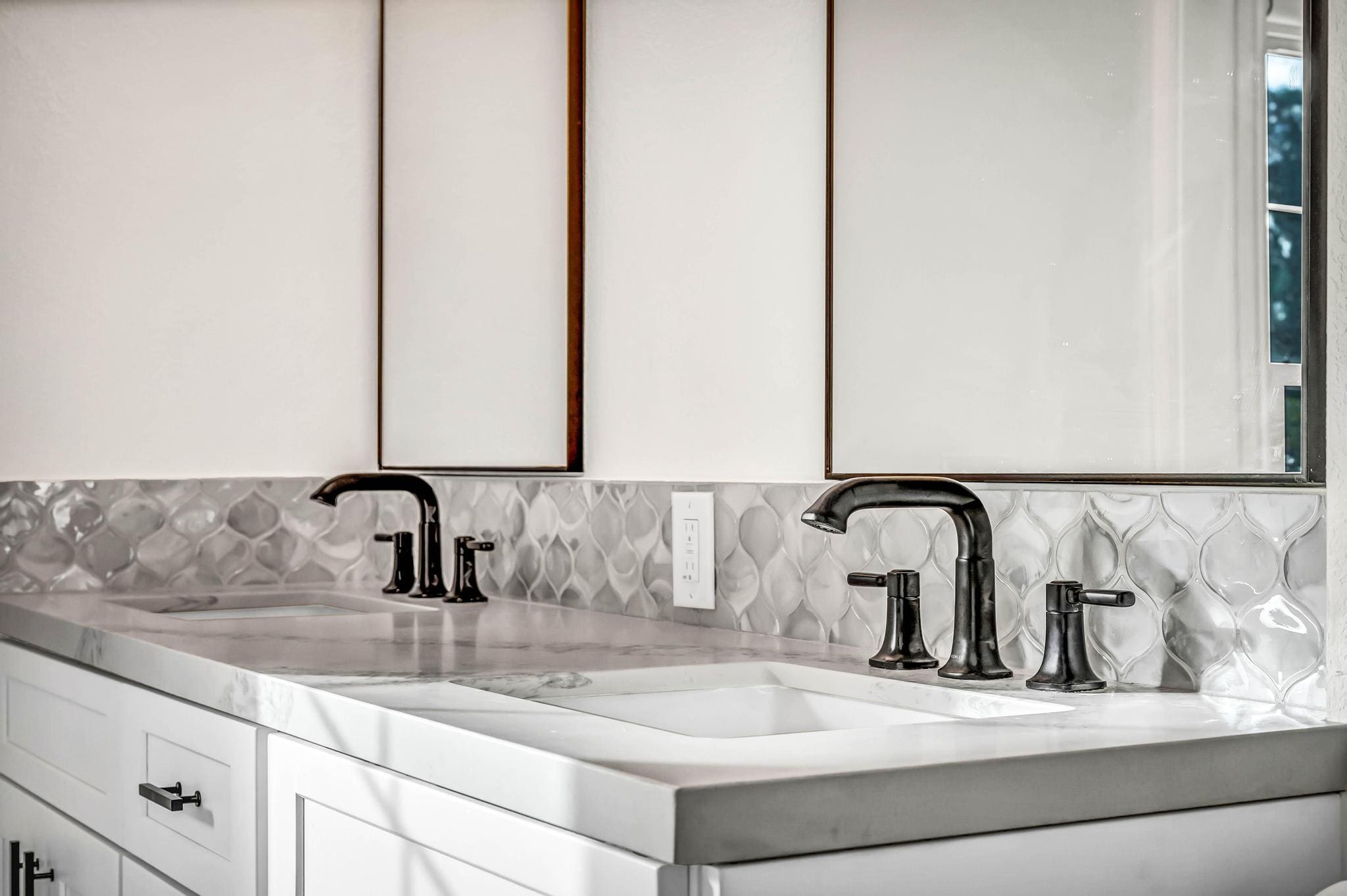 Double vanity with white sinks, dark faucets, and patterned tile backsplash