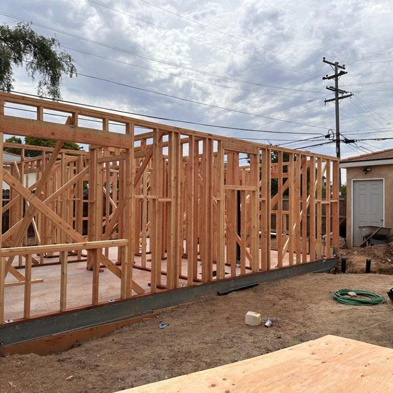 Wood framing of a house under construction with a cloudy sky