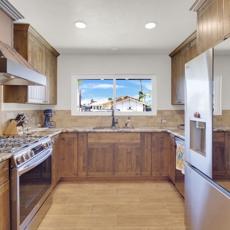 U-shaped kitchen with wooden cabinets, stainless steel appliances, and a window.