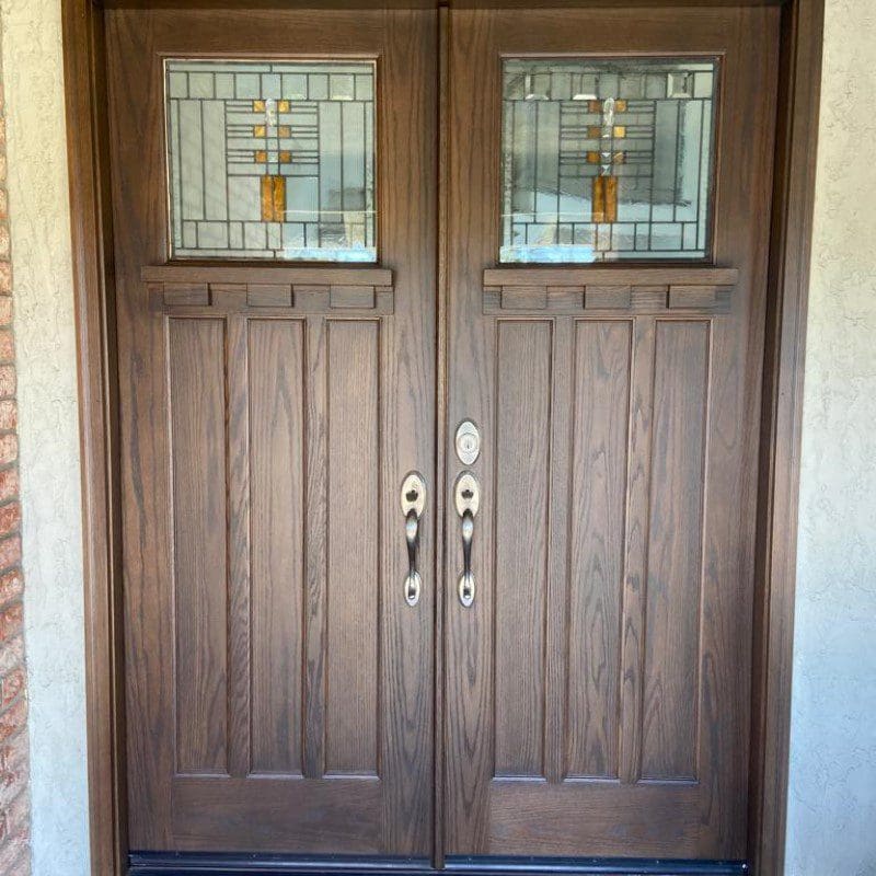 Double wooden doors with decorative stained glass panels and silver handles.