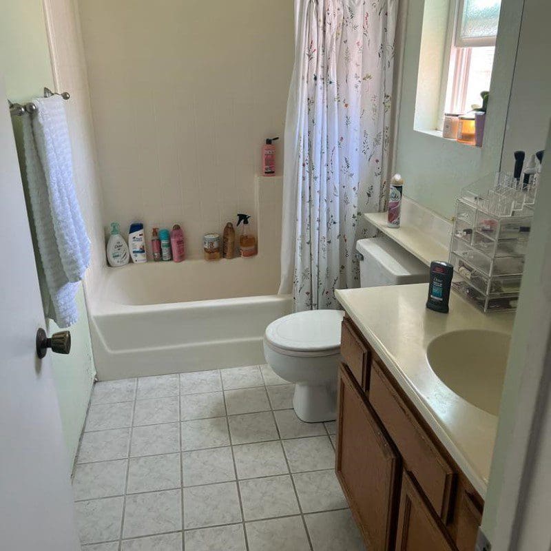 Small bathroom with a toilet, sink, bathtub, and various toiletries.
