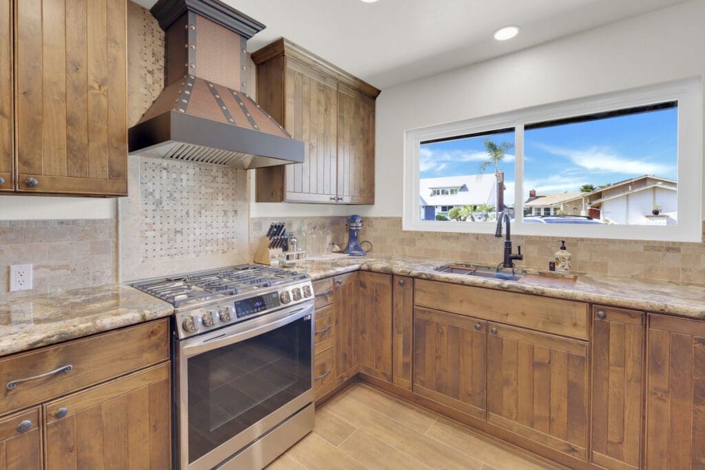 Modern kitchen with wooden cabinets, stainless steel appliances, and a window view.