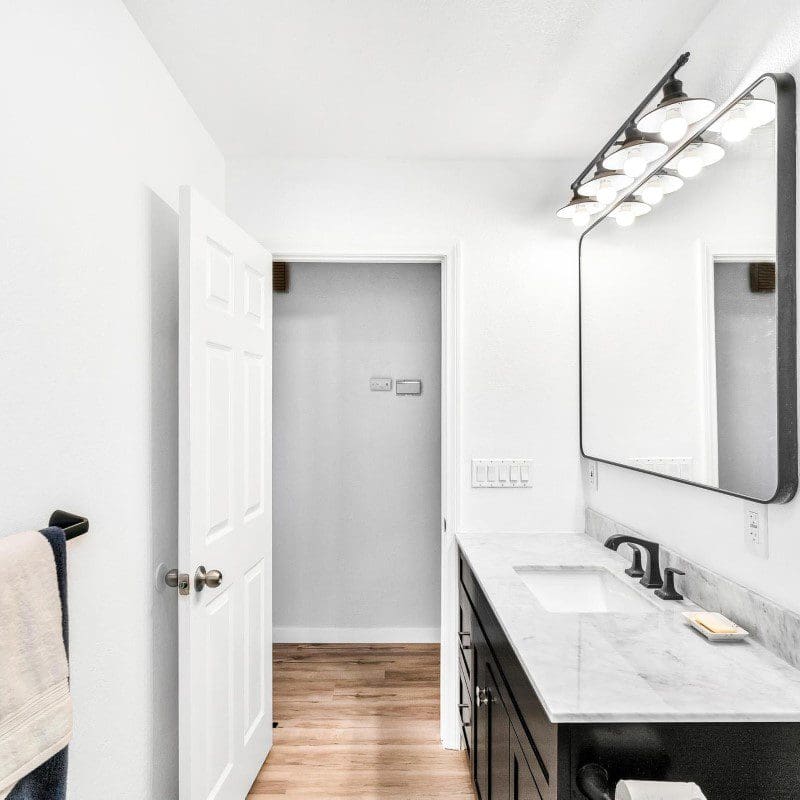 Modern bathroom with white walls, dark vanity, and large mirror
