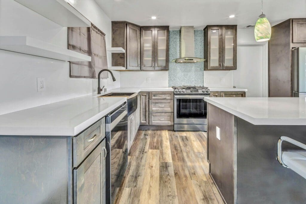 Modern kitchen with gray cabinets, white countertops, and wood flooring.