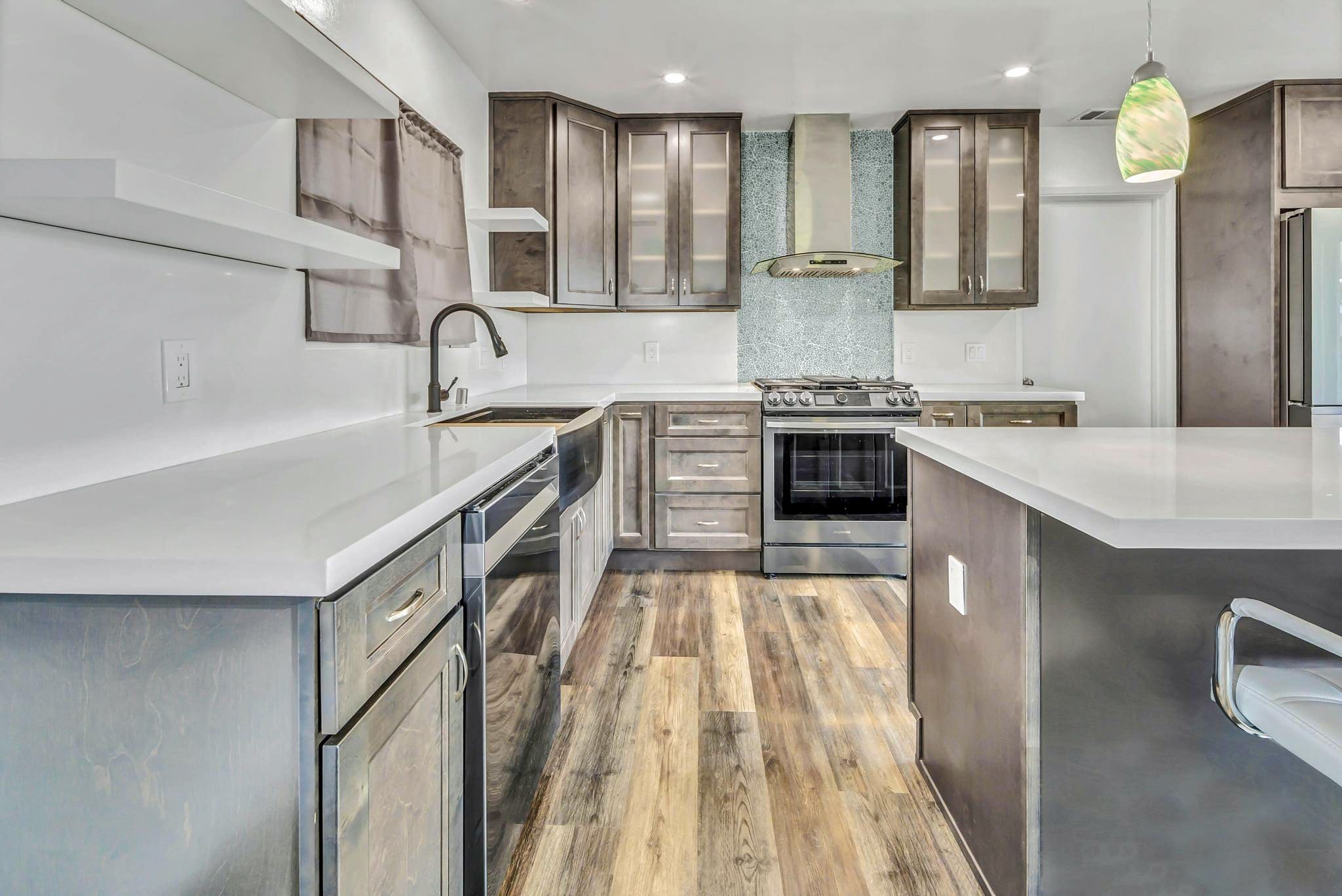 Modern kitchen with gray cabinets, white countertops, and wood flooring.