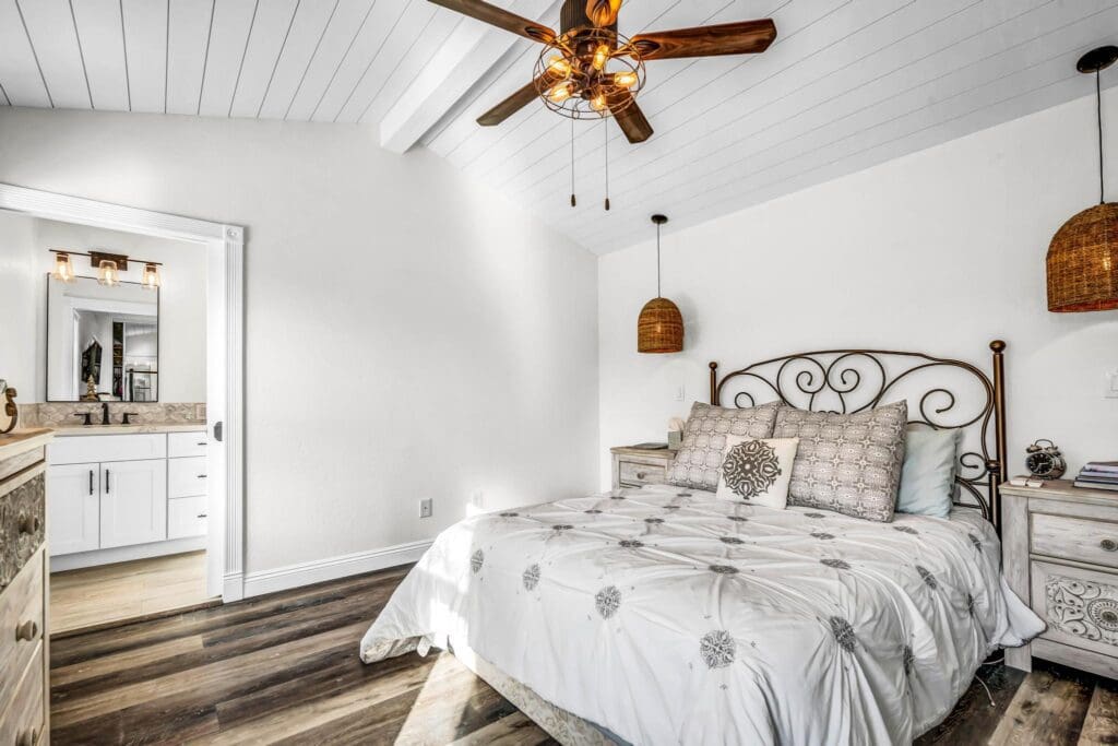 Bedroom with white walls, ceiling fan, and open door to bathroom.