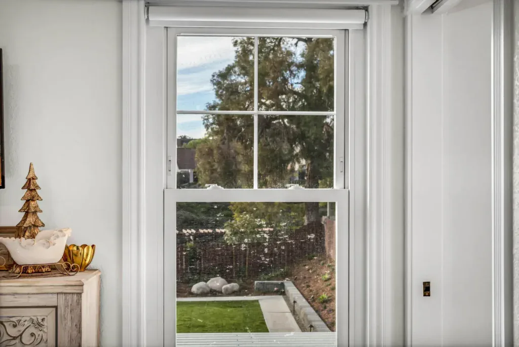 White framed window looking out onto a green lawn and trees