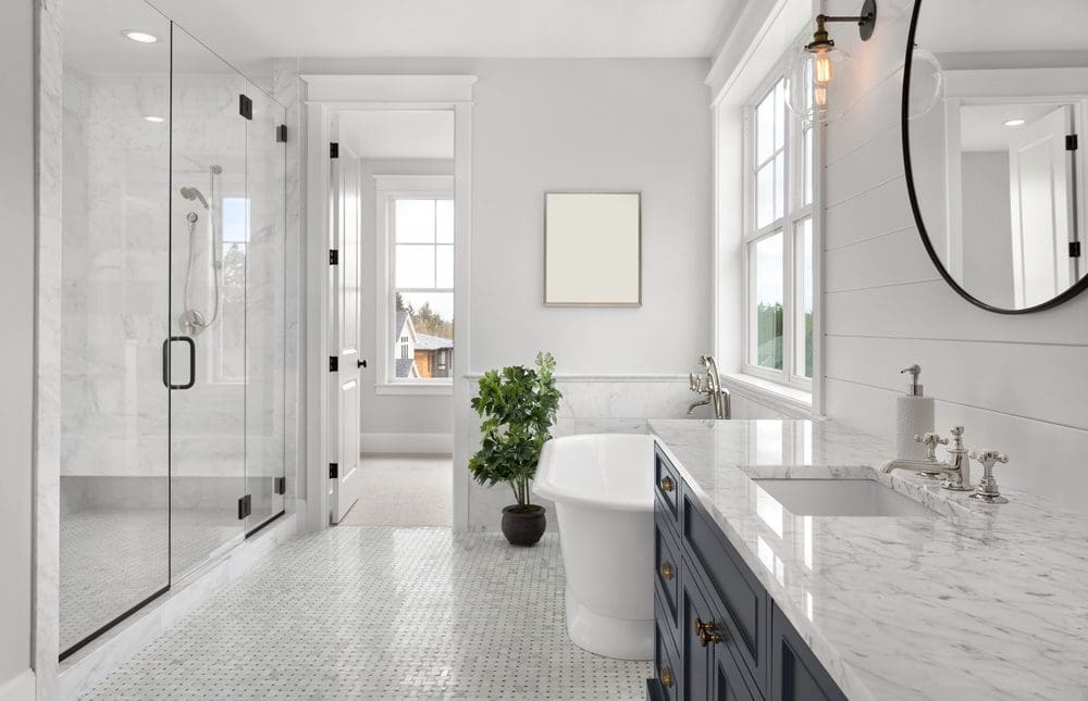 Modern bathroom with white marble, glass shower, and freestanding tub.
